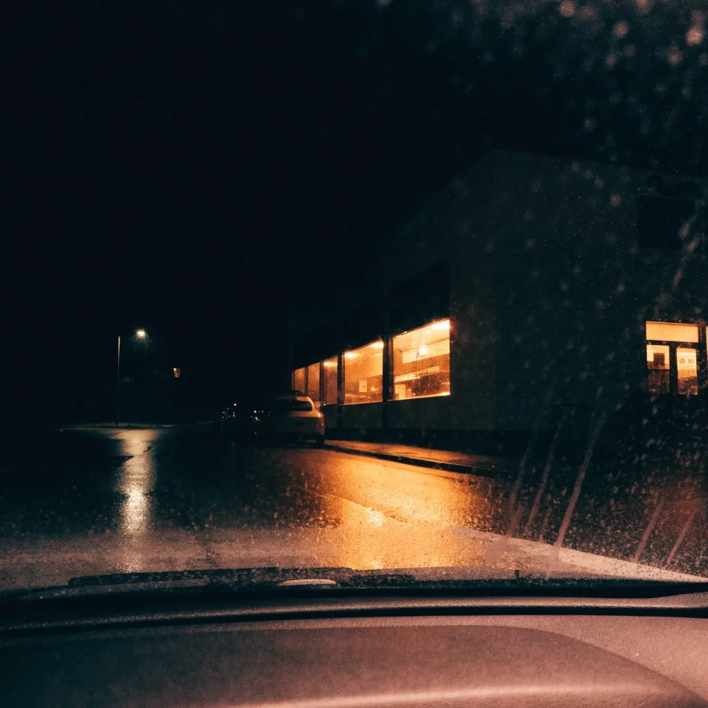 A diner seen from a car at night through rain on the windshield